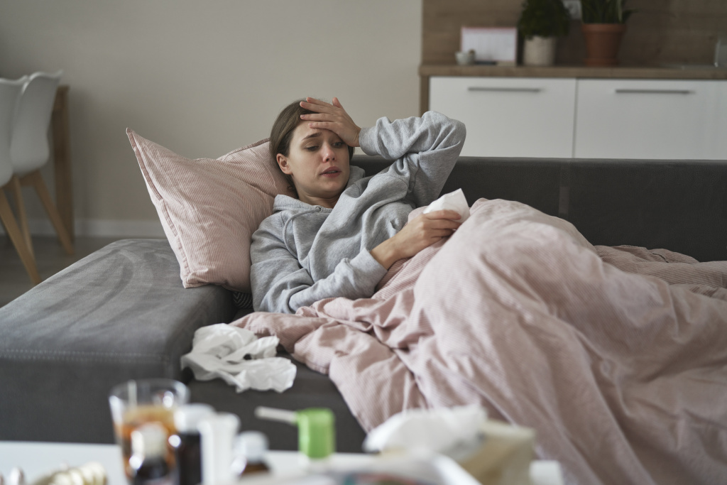 sick-woman-lying-down-duvet-looking-medicine-table.jpg