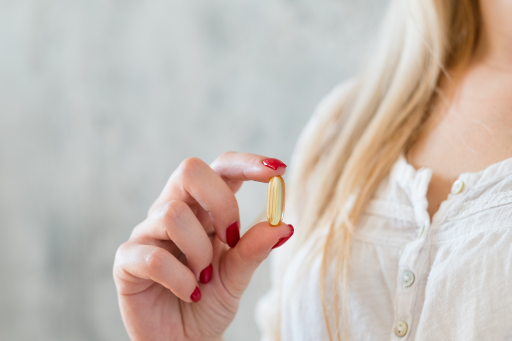 healthy-lifestyle-vitamins-consumption-woman-holding-fish-oil-capsule-fingers.jpg